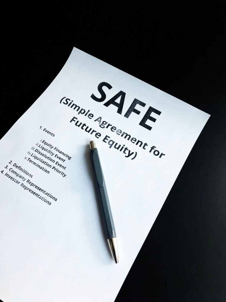 A person reviewing documents and photographs while making notes at a kitchen table.