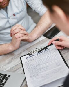 A concerned family reviews insurance papers together at their dining table, paperwork and a laptop spread out.