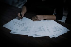A policyholder organizes a denial letter, insurance policy, photographs, and receipts at a kitchen table.