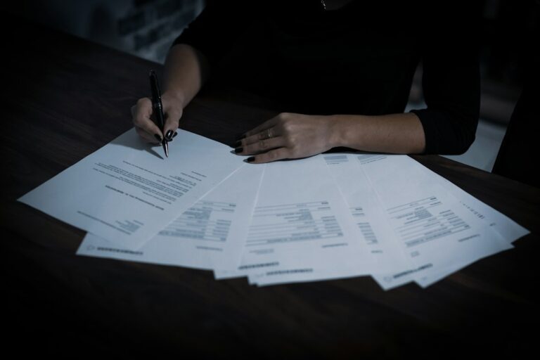 A policyholder organizes a denial letter, insurance policy, photographs, and receipts at a kitchen table.