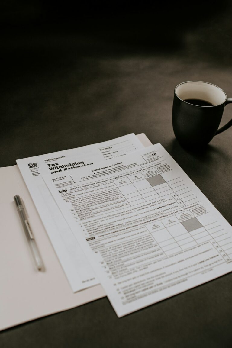 A person reviews paperwork and photos at a kitchen table, preparing documents for an insurance claim.
