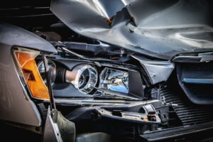 Driver reviews a repair estimate and accident photos beside a damaged vehicle.